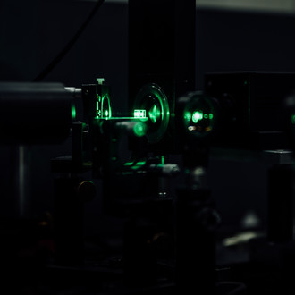 Photo of a lab in twilight with optical elements and a green laser beam
