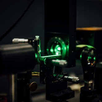Photo of a lab in twilight with optical elements and a green laser beam