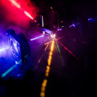 Photo of a dark lab with optical elements and laser beams of different wavelengths